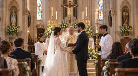 Catholic bride and groom exchange wedding vows before a priest during the Sacrament of Matrimony inside a church.