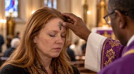 Catholic priest marking a woman's forehead with ashes during an Ash Wednesday service at the beginning of Lent.