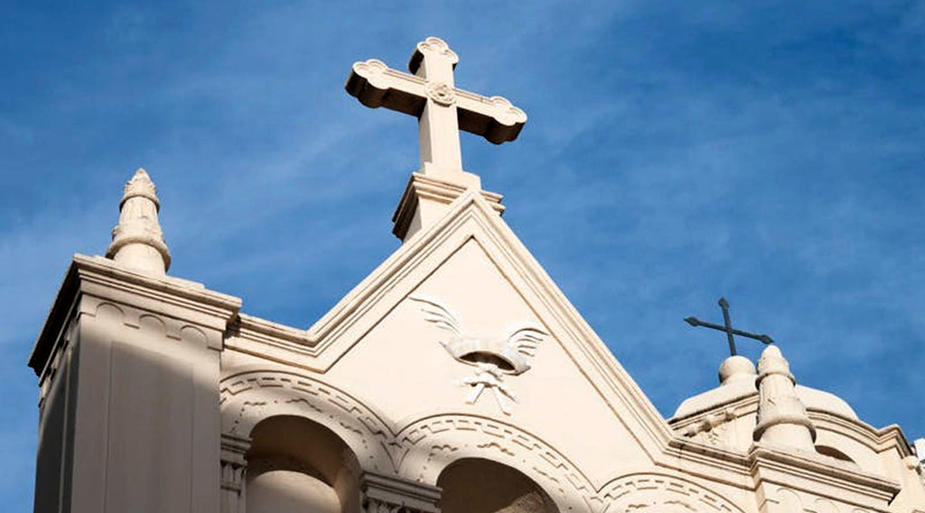 Cathedral spire with a budded cross against a blue sky