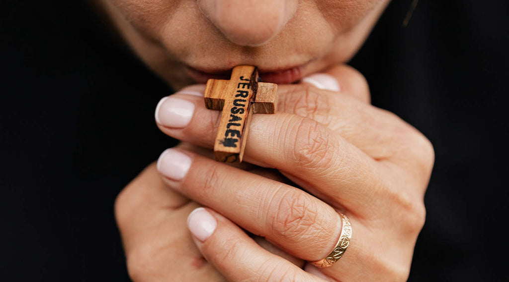 Hands holding a Jerusalem Olive Wood Cross