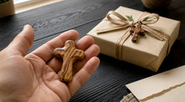 Olive wood comfort cross held in a hand beside a wrapped Christian gift, ready for a meaningful faith-filled present.
