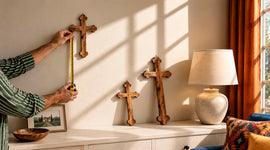 Hands measuring an olive wood wall cross while comparing three cross sizes for the perfect fit in a Christian home.