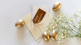 Decorative Easter eggs with a card and flowers on a light background