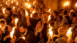 Eastern Orthodox Christians holding candles and a cross during the Holy Fire ceremony in Jerusalem