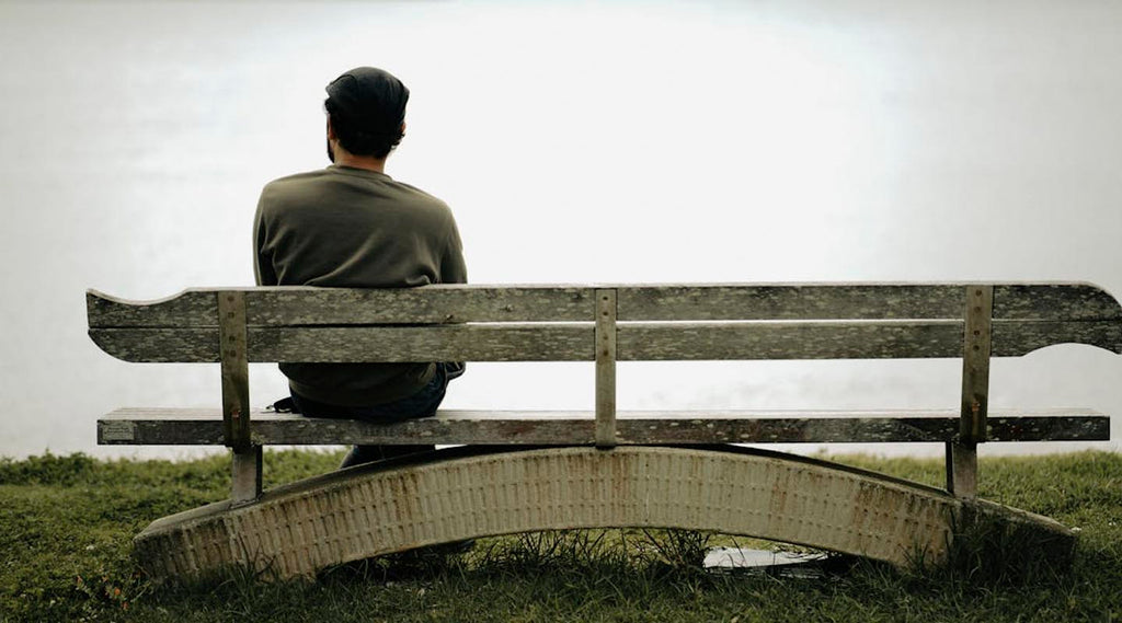 Person sitting on a bench looking out into a foggy landscape