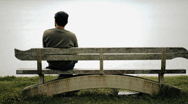 Person sitting on a bench looking out into a foggy landscape