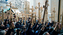 Many pilgrims wearing black and holding crosses above their head