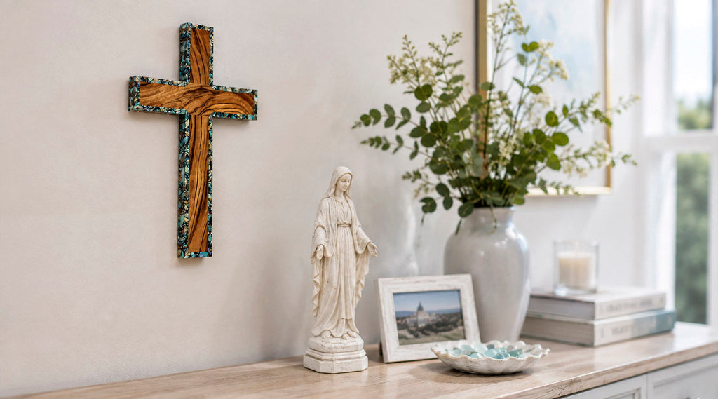 Olive wood wall crucifix above a home prayer shelf with a Virgin Mary statue, vase, framed photo, and natural light.