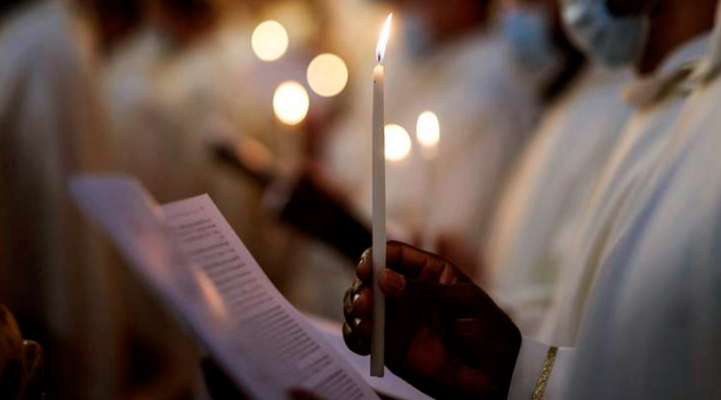 People praying, close up on a candle and The Lord's Prayer on paper