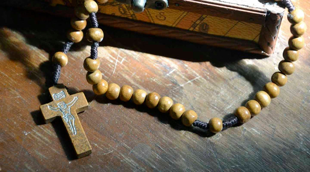 Olive wood rosary on a Bible laid down on a wooden table