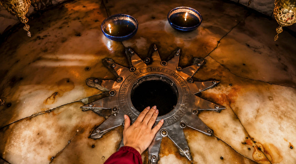 A pilgrim touches the Star of Bethlehem beneath the Nativity Altar inside the Church of the Nativity in Bethlehem