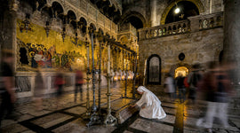 A pilgrim kneels in prayer beside the Stone of Anointing inside the Church of the Holy Sepulchre in Jerusalem