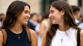 Two women smiling and talking while wearing a cross necklace and a crucifix necklace
