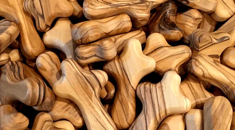 Olive wood Comfort Crosses, also knowen as Palm Crosses or Holding Crosses, piled in a bulk