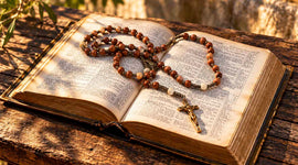 Traditional olive wood Catholic rosary resting on an open Bible beside a wooden cross in a Christian home