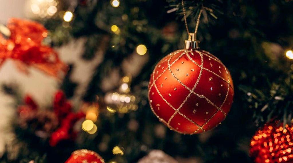 Red Christmas ornament on a decorated tree with blurred lights in the background