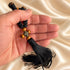 Hand holding a black 50-knot Chotki with wooden beads and bronze-tone cross