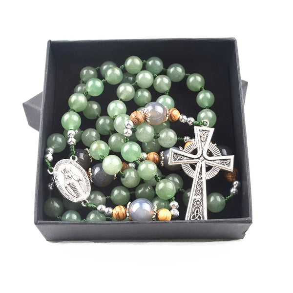 A handmade Irish Rosary with green aventurine and jade beads, a Virgin Mary medal and Celtic cross, laid in a black box.
