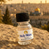 A bottle of 'Holy Water From the Blessed River of Jordan', on a rock with a blurred Jerusalem in the background.