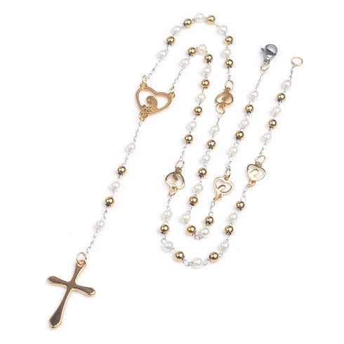 Elegant white pearl rosary with gold cross and engraved heart charm on white background.