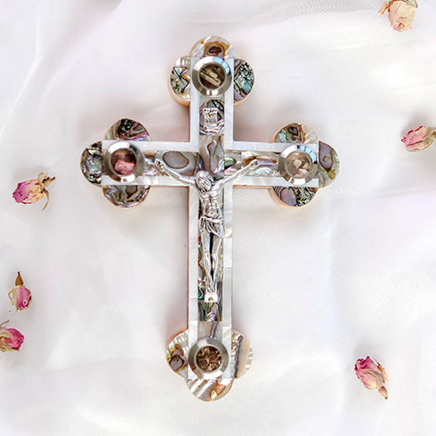 Elegant full size budded cross made from olive wood, featuring a silver-toned crucifix, mother of pearl inlay, and Four Holy Land Elements, styled with soft rose petals on a white backdrop.