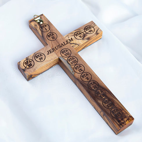 Latin cross made of olive wood with Stations of Cross and Jerusalem engraved on the back photographed against white background.