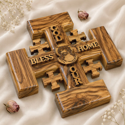 Jerusalem Cross from olive wood, featuring engraved blessings and Jesus Christ's face, resting on a white surface.