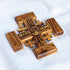Jerusalem Cross carved from olive wood, featuring engraved blessings and Jesus Christ's face, resting on a white surface.