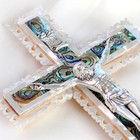 Detailed image of a classic Latin olive wood cross featuring a silver crucifix, polished Mother of Pearl green and white inlays.