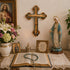 Religious items including a cross, statue of a Virgin Mary, flowers, and an open book with a rosary on a table.
