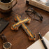 Wooden cross on a wooden desk with a cup, phone, glasses, and pen.