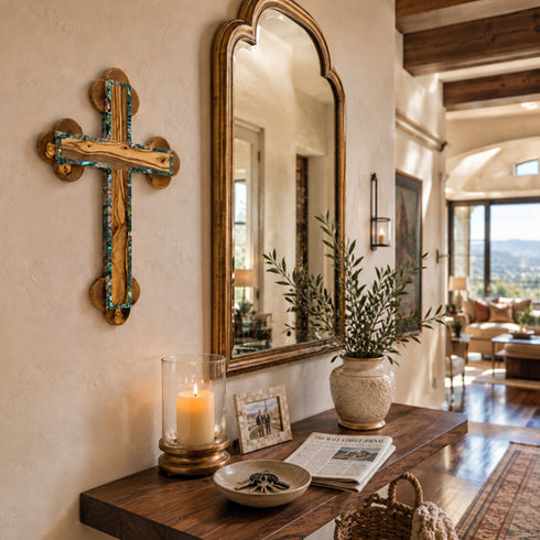 Decorative cross, mirror, candle, and plants on a wooden console table in a home setting.