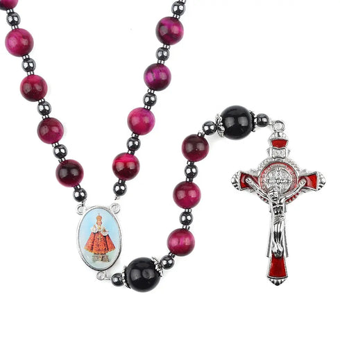 Rosary featuring red Tiger Eye beads, a Child Jesus center medal and a red St.Benedict crucifix, against white backdrop.