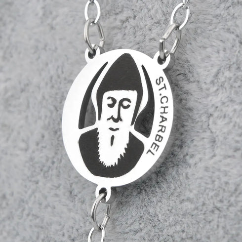 St.Charbel stainless steel rosary with polished beads on neutral grey backdrop.