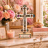 Decorative cross with Jerusalem inscription on a table with flowers and books.