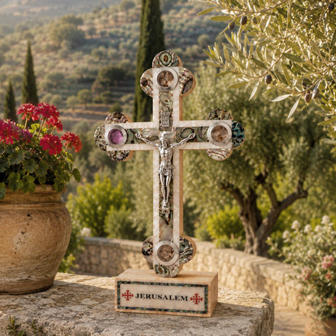 Decorative cross with 'Jerusalem' inscription on a stone surface with a scenic background.