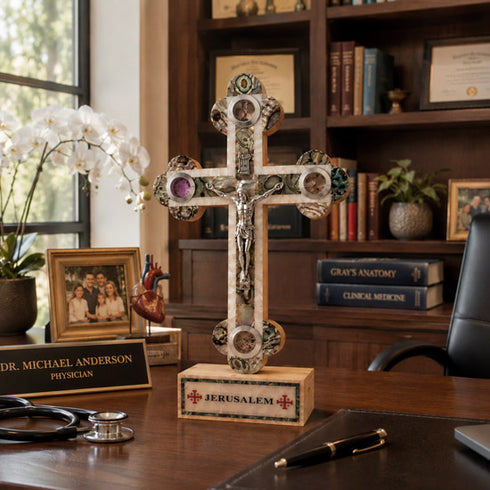 Decorative cross on a desk with books and a family photo in the background