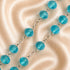 A close-up of a beaded chain necklace with faceted turquoise blue beads connected by silver-toned links.