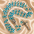 A rosary with light blue beads and silver-tone metal links and a crucifix, on a beige satin fabric background.