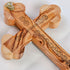 Zoomed image of the back of a handcrafted budded olive wood cross, placed on a white background.