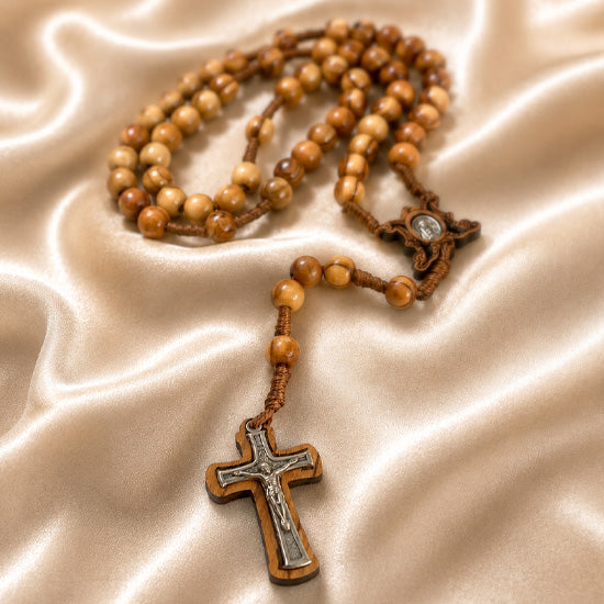 Olive wood rosary with crucifix and Marian centerpiece on a satin fabric background with soft focus