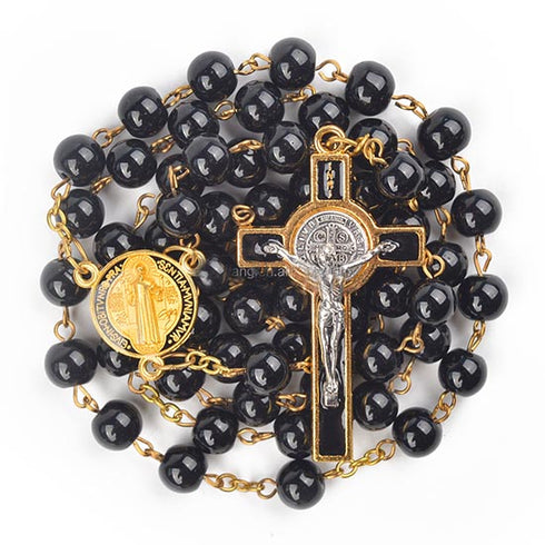Black glass bead rosary with gold accents and St Benedict crucifix on a white background.