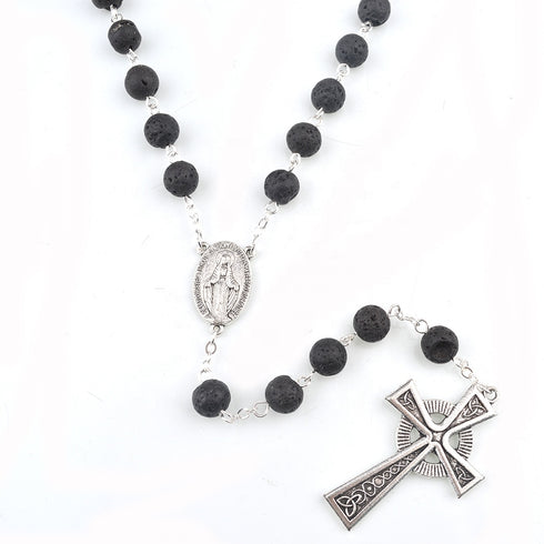 Black lava stone rosary with silver Celtic cross and Miraculous medal on a white background.