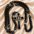 Black beaded rosary with black and white knotted cord, a black cross with a silver-toned circular St. Benedicty medallion.