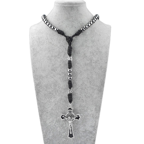 Black rosary necklace with silver cross on a mannequin bust.