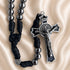 Black cord rosary with metallic silver beads and a silver crucifix, on a beige satin background.