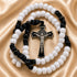 A Catholic rosary with white beads, blue cord, and a silver-tone crucifix, on a draped satin fabric background.
