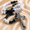 A white beaded rosary with a silver-tone crucifix, displayed on a beige satin fabric background.