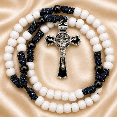 A rosary with white beads, black accent beads, and dark blue knotted cord, featuring a silver-tone crucifix.