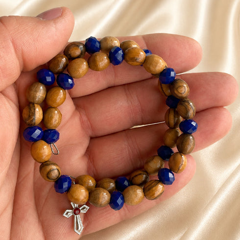 Bracelet held in hand: olive wood and dark blue faceted beads with silver cross charm